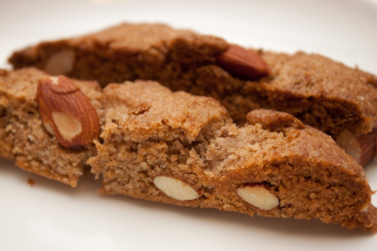 Almond biscotti stacked on a plate, cut faces showing whole almonds